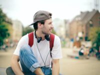 man in white shirt wearing black cap and black headphones
