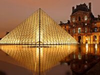 Impresionante vista nocturna de la Pirámide del Louvre iluminada y su reflejo en París, Francia.