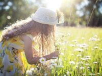 Una niña disfruta recogiendo flores en un prado iluminado por el sol, encarnando la alegría pura y la inocencia.