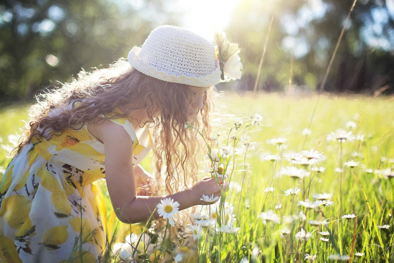 Una niña disfruta recogiendo flores en un prado iluminado por el sol, encarnando la alegría pura y la inocencia.