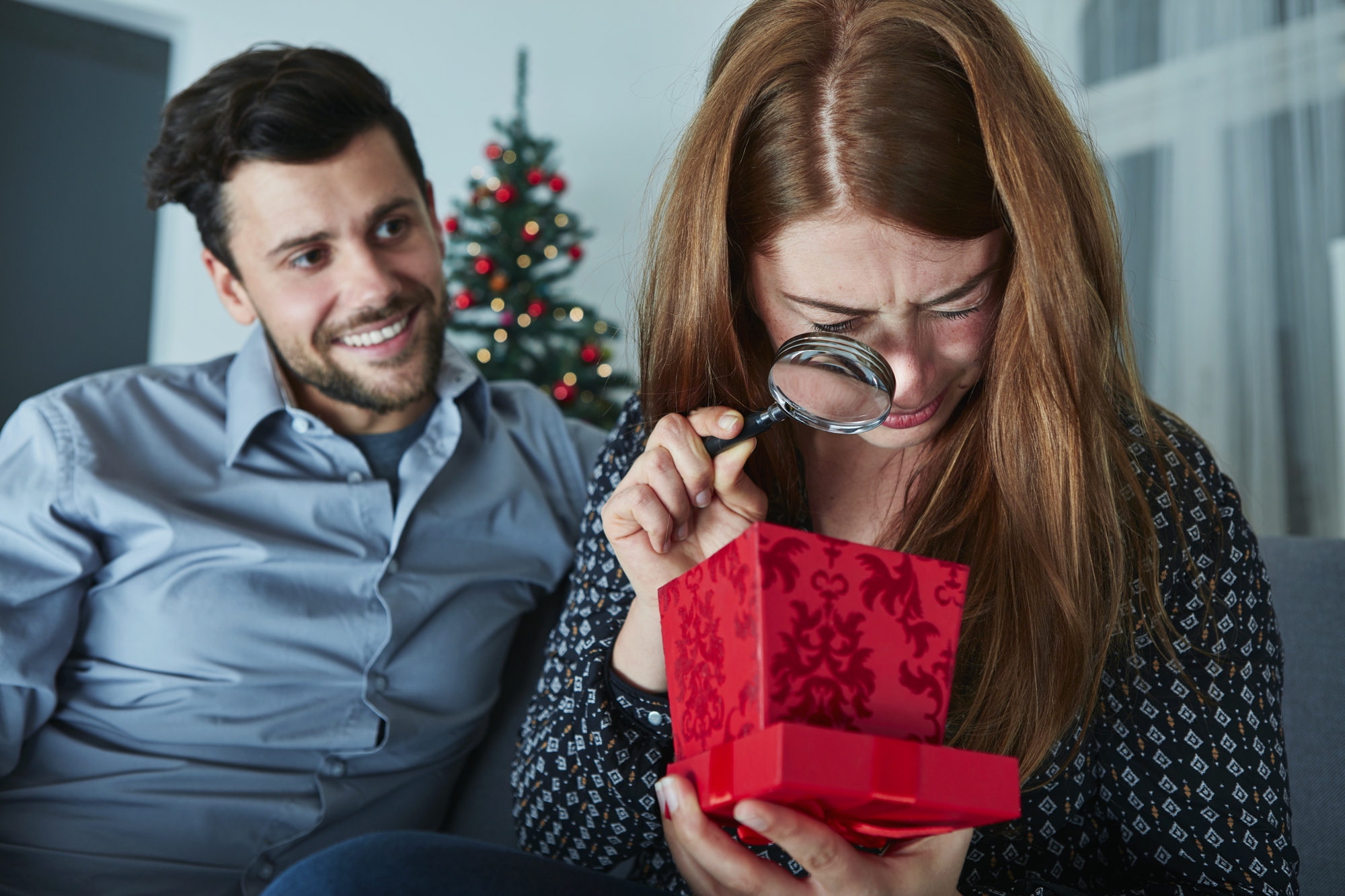 Chica mira escéptica su regalo con lupa